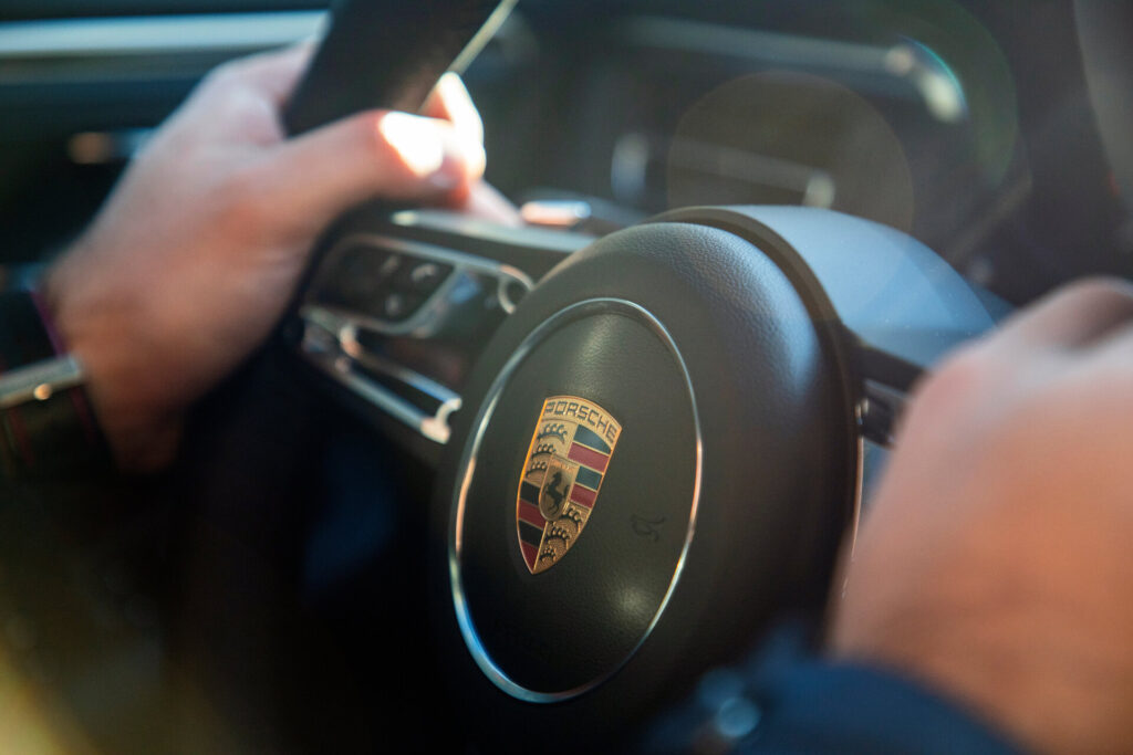 Hände am Steuer eines Porsche Macan, fünftüriger Luxus-Crossover-SUV.