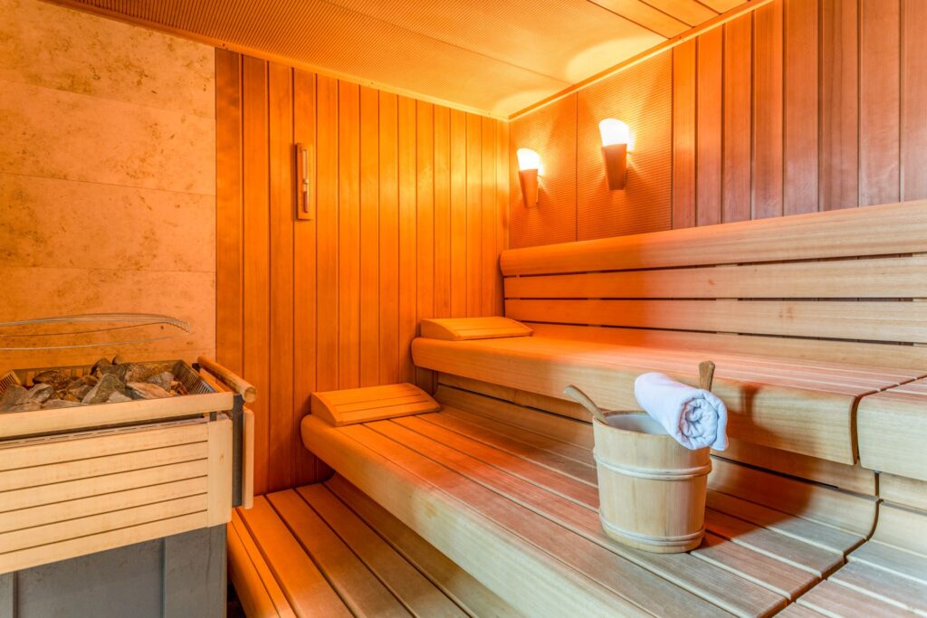 Sauna mit Holzinterieur und Aufgusseimer.